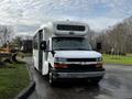 A 2015 Chevrolet Express van with a white exterior and a large front windshield designed for passenger transport