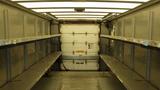 A 2011 Ford Econoline cargo van interior with metal shelving on both sides and a rear door visible in the background