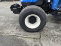 2007 New Holland TN70A tractor tire with a black rubber surface and white rim positioned on a gravel surface