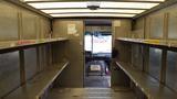 Interior of a 2011 Ford Econoline with metal shelves on both sides and a closed partition at the rear