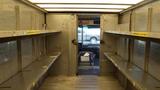 Interior of a 2006 Ford Econoline with metal shelves on either side and an open door at the rear leading to the front cabin