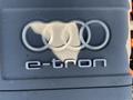 A close-up of the Audi logo featuring four interlinked rings above the word e-tron