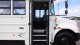 A 2015 International PC105 school bus with an open door revealing empty seats inside and steps leading up into the bus