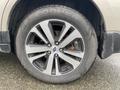 A close-up of a silver alloy wheel from a 2019 Subaru Outback with a Cooper tire showing multiple spokes and a visible brake disc