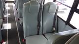 Interior view of a 2015 International PC105 bus showing two rows of gray upholstered seats with seatbelts