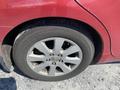 A maroon 2007 Toyota Camry Hybrid tire with a silver alloy wheel featuring five spokes and a brand label on the tire tread