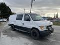 A white 2001 Ford Econoline van with black wheels parked on a gravel surface