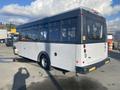 A 2018 Chevrolet Express bus with a white body and large windows is parked with its rear facing the viewer