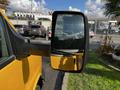 Side mirror of a yellow 2017 GMC Savana showing reflective clouds and nearby vehicles in the background