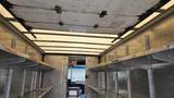 Interior of a 2006 Ford Econoline with metal shelving on both sides and a clear ceiling above