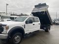 A white 2021 Ford F-550 cab and chassis truck with an elevated dump bed showcasing a large cargo area and dual rear wheels