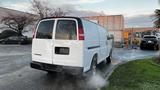 A 2005 Chevrolet Express van in white color with a missing rear license plate and visible steam rising from the back