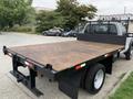 2012 Ford F-550 flatbed truck with a wooden surface and a metal mesh fence on the back