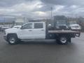 A white 2015 Chevrolet Silverado 3500HD with a flatbed, showcasing its profile with chrome wheels and a spacious cab