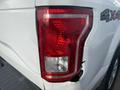 Close-up of the rear tail light of a white 2017 Ford F-150 showing visible damage to the housing and lens