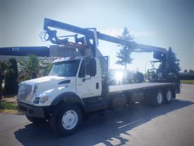 A 2006 International 7500 truck with a crane attached to the bed and a raised platform for equipment or materials