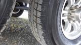 Close-up of a tire from a 2021 Forest River 312BH East To West Della Terra showing tread pattern and metal rim