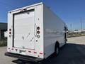 A 2011 Ford Econoline van with a white exterior and a boxy shape showcasing rear doors and red tail lights