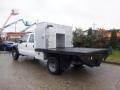 A white 2009 Ford F-450 SD with a flatbed and a metallic storage compartment on the rear