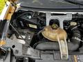 2015 Chevrolet Express engine compartment showing the coolant reservoir and battery with various hoses and wires connected