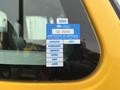 A yellow 2007 International 4300 truck with a blue and white 2025 certificate of approval sticker displayed on the window