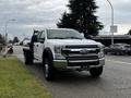 A 2021 Ford F-550 pickup truck with a flatbed design in a white color parked on the side of the road