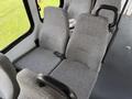 Interior of a 2010 Ford Econoline showing gray fabric seats with armrests and seatbelts