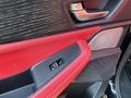 Close-up of the red and black interior door panel of a 2023 Acura MDX featuring a speaker grille and door handle