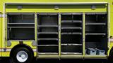 A yellow 1995 Freightliner FLL086 truck with open side compartments revealing empty shelves and storage spaces