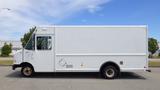 A white 2011 Ford Econoline delivery truck with a large cargo area and a side door parked on a street