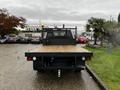 A green 2020 Ford F-350 SD flatbed truck with a wooden deck and a metal mesh cab guard