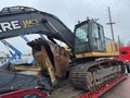 A 2014 John Deere 350G excavator with a large bucket and tracks is positioned on a trailer ready for transport