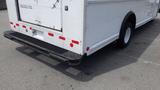 A white 2011 Ford Econoline van viewed from the rear showing its bumper and part of the cargo area with red reflective tape and a textured step cover