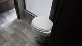 A white toilet in a small bathroom area with a light-colored floor and surrounding walls