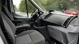 Interior view of the front seats and dashboard of a 2017 Ford Transit with gray upholstery and a spacious cabin design