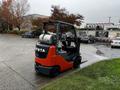 A 2017 Toyota 8FCGCU25 forklift with a red and black body and two gas cylinders on the back parked in a lot