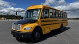 A yellow 2014 Freightliner Thomas bus with a black front, featuring large windows and an emergency light on top