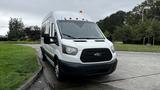 A 2017 Ford Transit van with a white exterior and multiple amber lights on the roof is parked on a concrete surface