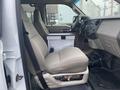 Interior of a 2009 Ford F-450 SD showing the driver's side with a beige cloth seat and a metal container positioned on the floor