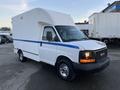 A 2009 GMC Savana van with a high top and a blue stripe along the side parked with visible chrome wheels