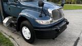 A blue 2009 International 4300 truck featuring a large front grille round headlights and side mirrors with a prominent black front bumper