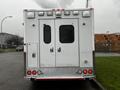 Rear view of a white 2016 Chevrolet Express with a boxy design featuring dual doors emergency lights and reflectors