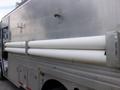 A silver Morgan Olson Workhorse W42 delivery truck with two long white cylindrical pipes attached to its side