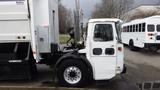 A 2007 Autocar WXLL garbage truck with a boxy cab and large wheels is parked, featuring a prominent exhaust stack and various attachments on the driver's side