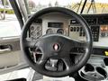 Steering wheel and dashboard of a 2014 Kenworth T370 showcasing gauges buttons and controls
