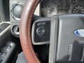 Close-up of a 2010 Ford F-550 steering wheel with a brown leather cover featuring control buttons for cruise control settings