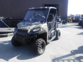 A 2018 Polaris Ranger XP 900 off-road vehicle with a camouflage pattern and large tires parked on a concrete surface