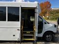 A 2015 Chevrolet Express bus with open double doors and steps leading into the interior seats visible through the doorway