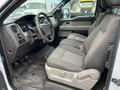 Interior view of a 2010 Ford F-150 showing two grey cloth seats and the dashboard with control buttons and an infotainment system