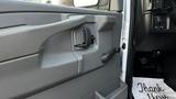 Interior door handle of a 2005 Chevrolet Express with a gray plastic panel and a thank you note on the floor mat